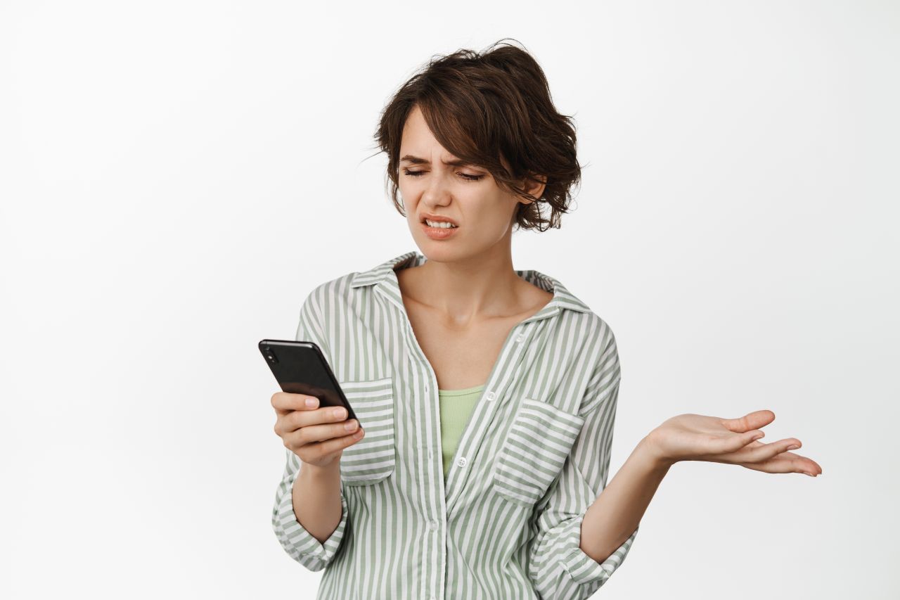 frustrated-young-woman-looking-mobile-phone-screen-complicated-shrugging-frowning-disappointed-standing-white.jpg